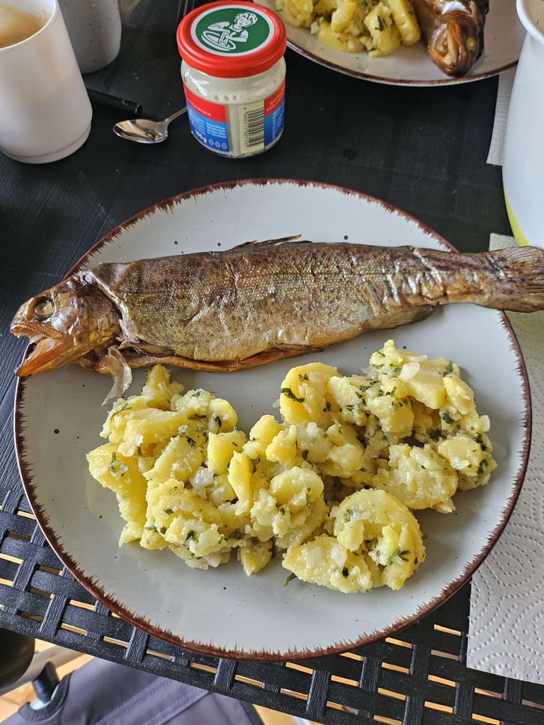 Gegrillter Fisch mit Kartoffelsalat auf einem gedeckten Tisch